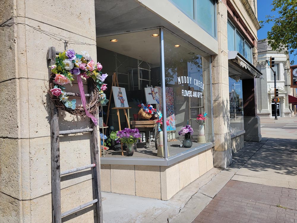 A boutique with a ladder and flowers decorating outside wall in Junction City